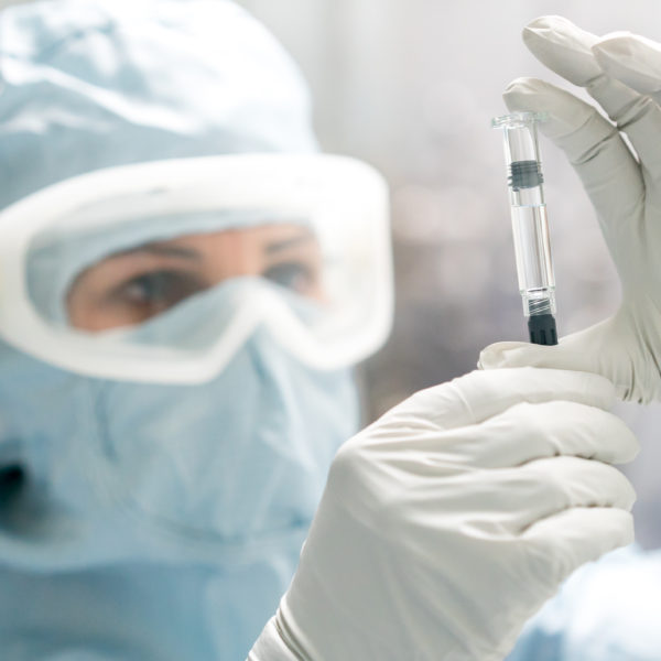 Final sterile filled syringe held by manufacturing tech